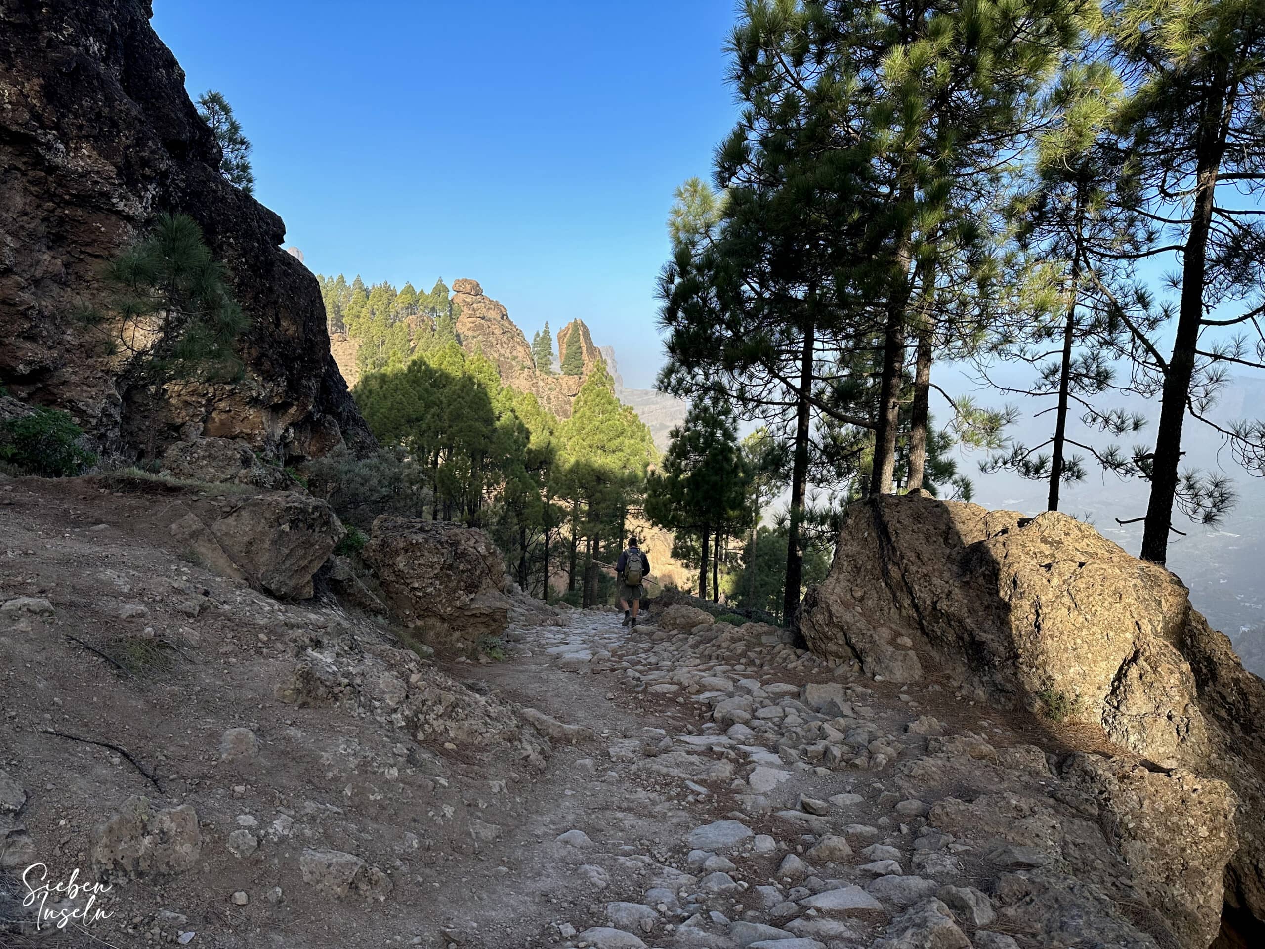 Hiker on the paved path down towards Press de los Hornos