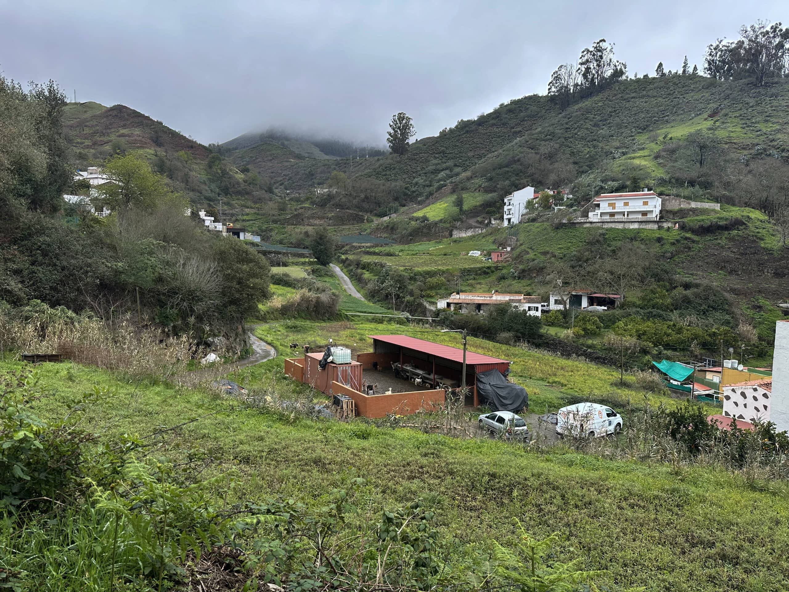 Vista desde la ruta de senderismo hacia pequeñas aldeas, campos y colinas verdes
