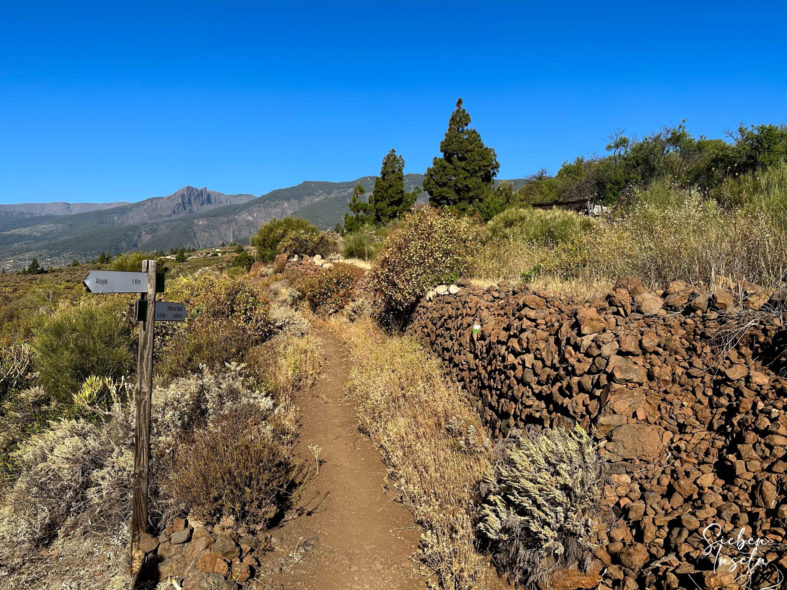Wanderweg führt zwischen alten Steinmauern vorbei an Ruinen und alten Brunnen