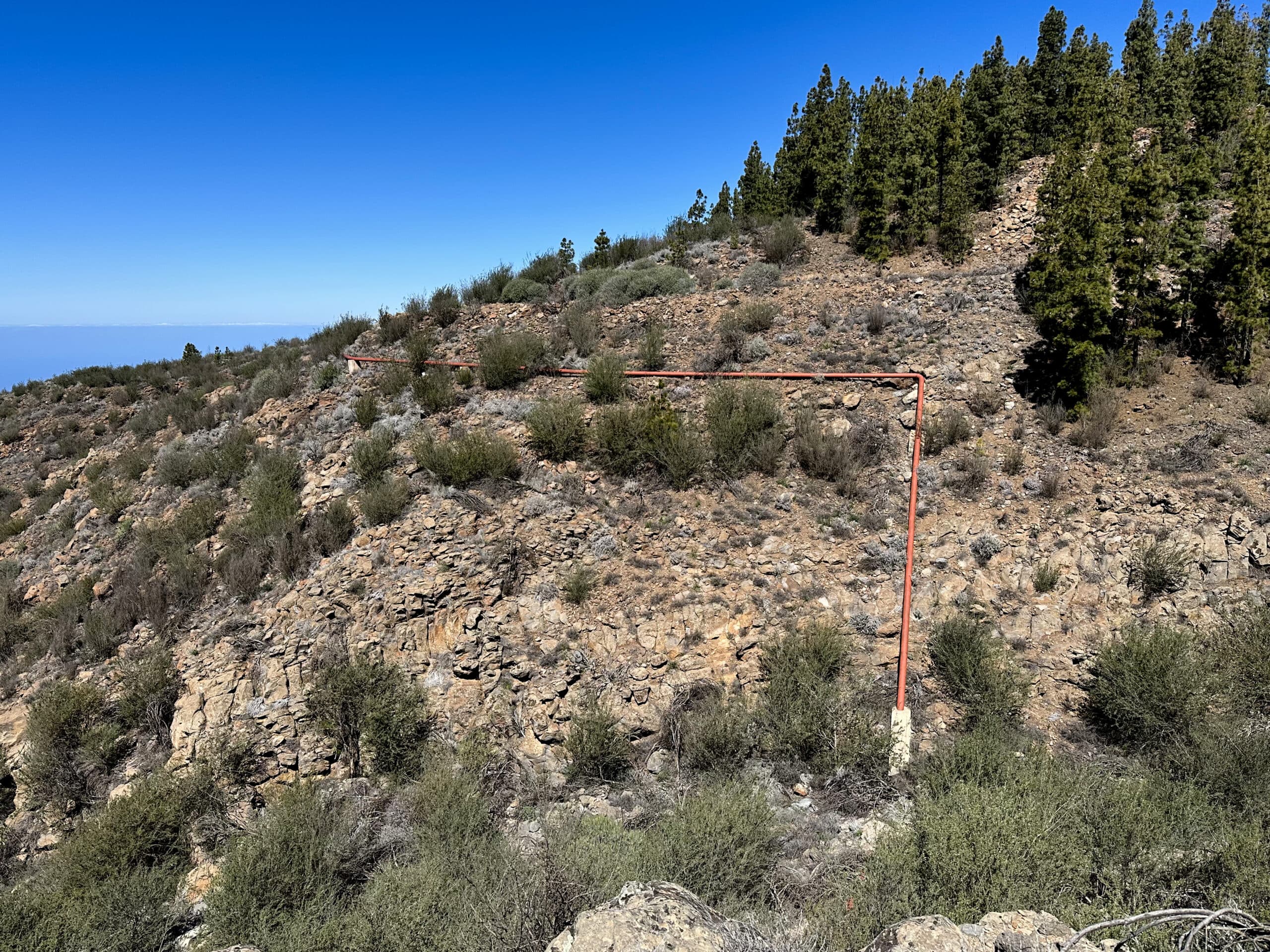 Vista desde arriba del barranco sobre el que se extiende la tubería roja. Poco antes pasaste por debajo de esta tubería y giraste a la izquierda. Aquí puede mirar hacia el barranco o acortar la caminata como se describe.

