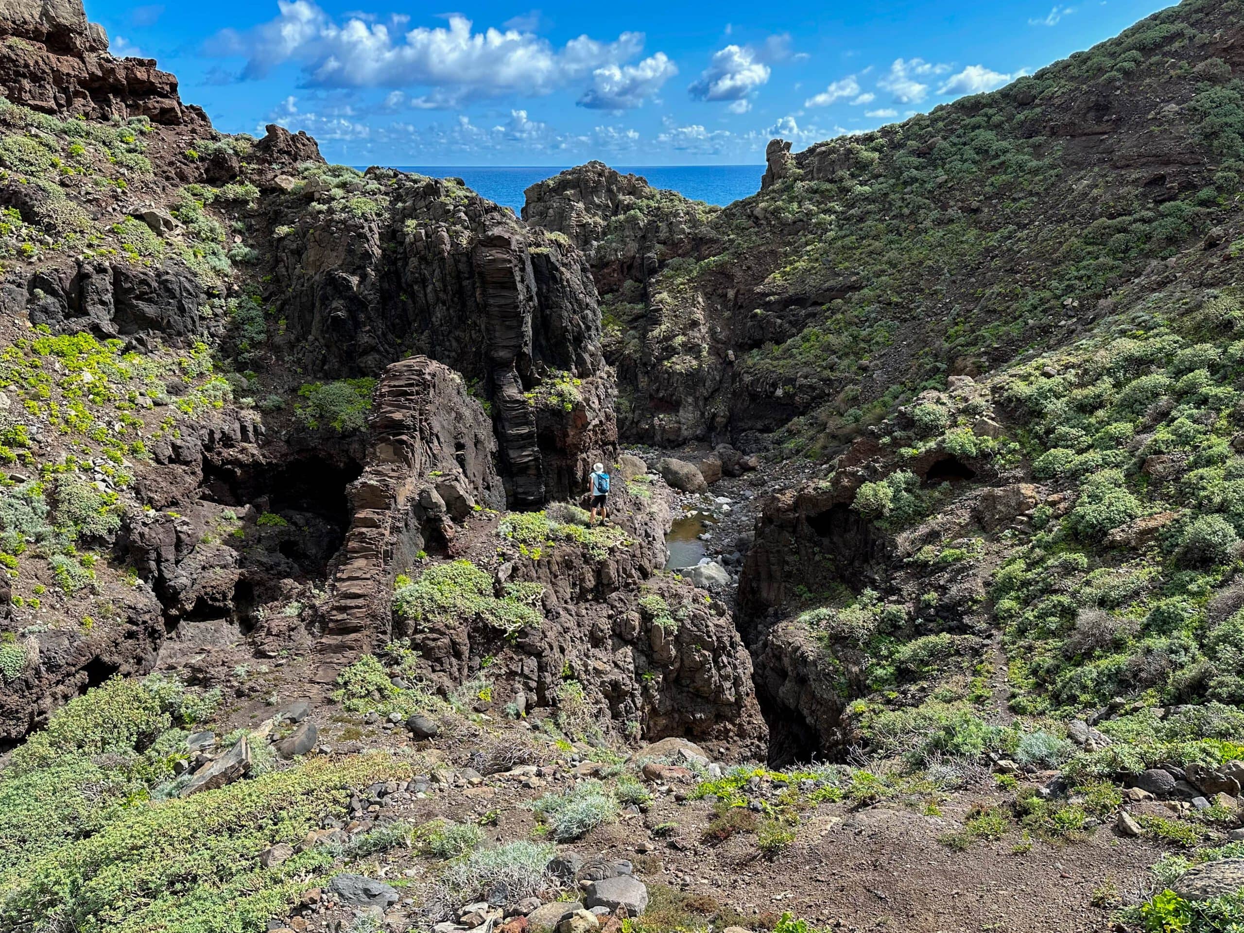 Hiker in Barranco Anosma in front of a rock bar with a view of Barranco and the Atlantic Ocean