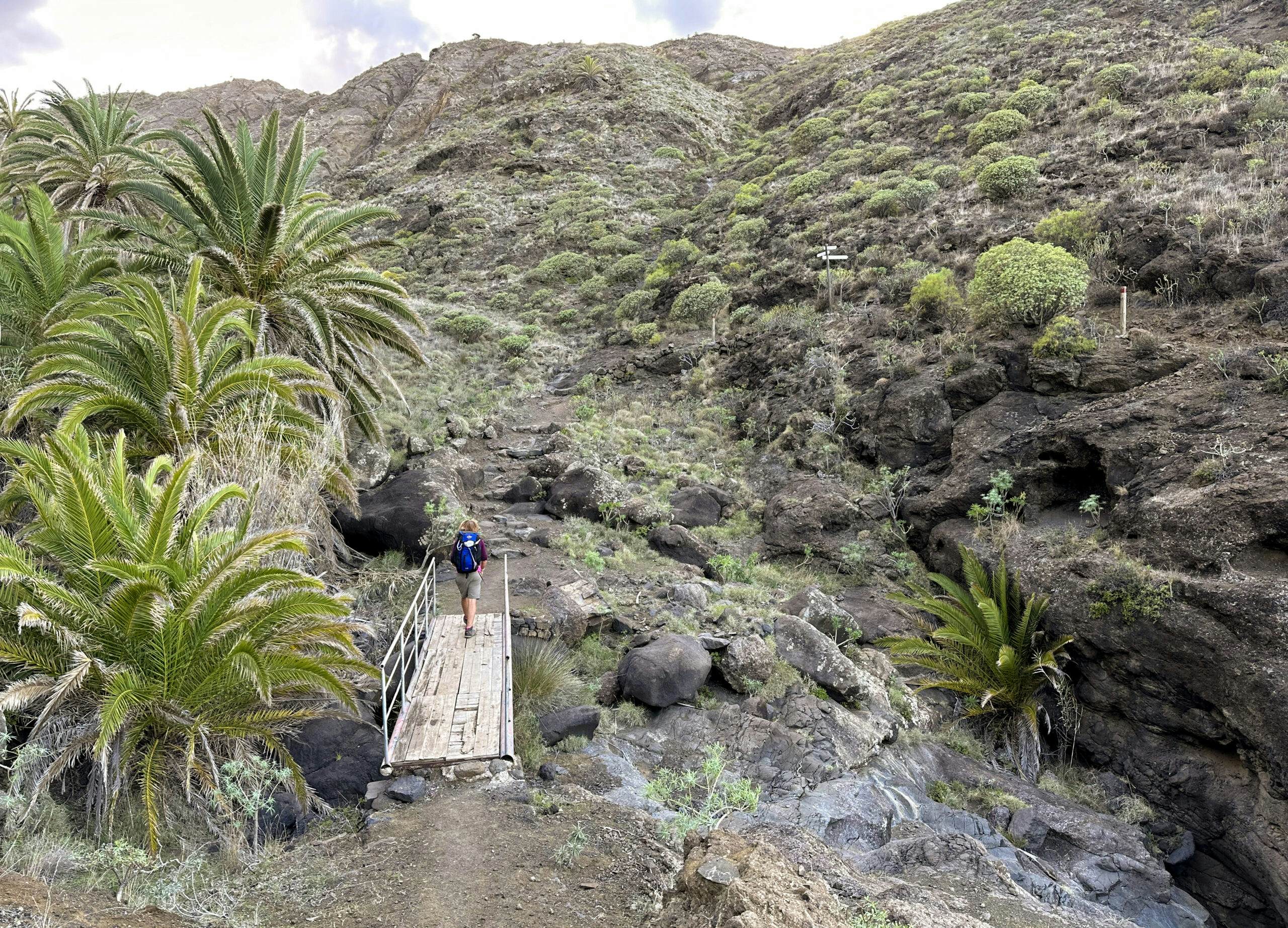 Hiker on the GR-132 long-distance hiking trail on a bridge on the coast off La Caleta