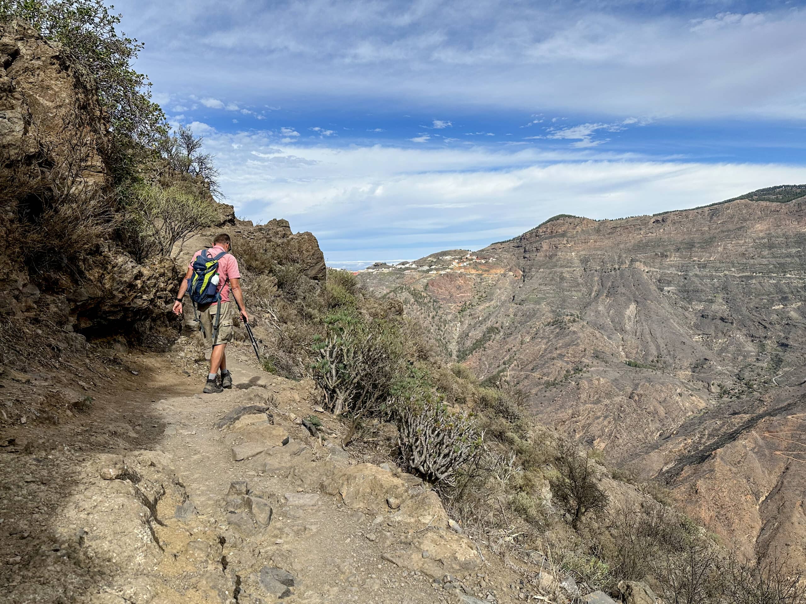 Hiker on the hiking trail at Roque Bentayga with a view of the Barranco Tejeda and Artenara in the background